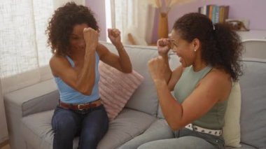 Kadın arkadaşlar içeride gülüyor, sohbet ediyorlar. Oturma odasında sohbet ediyorlar. Keyifli kutlamalar yapıyorlar.