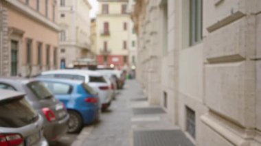 Roma 'nın eski kasabasındaki İtalyan caddesinin bulanık görüntüsü, park halindeki arabaların ve Bokeh etkisindeki tarihi binaların rüya gibi bir atmosfer yaratması.