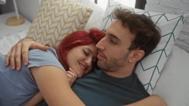 Çift sıcak yatak odası ortamında sevgi dolu bir şekilde kucaklaşıyor, duygusal bağlantılarını ve kapalı alandaki samimiyetlerini vurguluyor..