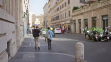 Roma, İtalya 'da tarihi bir cadde boyunca yürüyen bulanık bir mimari ve canlı bir şehir ortamı sergileyen insanların odaksız sahnesi..