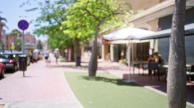 Sokak manzarası çözünmüş yayalar, açık hava araçları ağaçlık bir yol boyunca park edilmiş ve kalabalık bir şehir alanı üzerinde bokeh etkisi