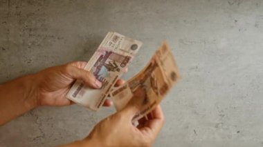 Eller, arka planda birkaç Rus rublesi sayıyor.