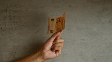 Elde tutulan 50 avroluk banknot, somut arka plan, sergilenen para değişimi veya nakit işlemleri minimalist bir ortamda