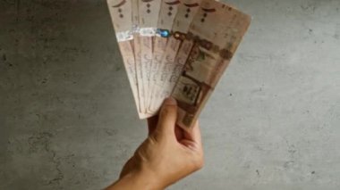 Suudi Arabistan 'da para ve finans kavramını gösteren somut bir arkaplan karşısında el ele tutuşan Suudi riyal paraları