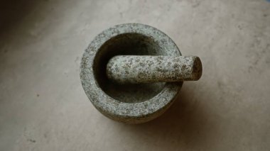 Beton yüzey üzerindeki taş harç taşra ortamında baharat öğütmek için geleneksel bir mutfak aleti sergiliyor.