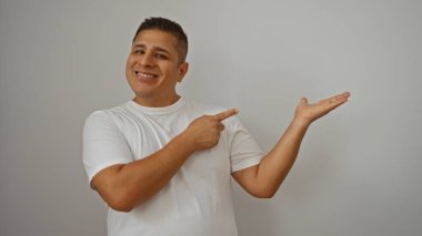 İzole edilmiş beyaz bir arka planda gülümserken avucunun içini gösteren genç bir İspanyol.