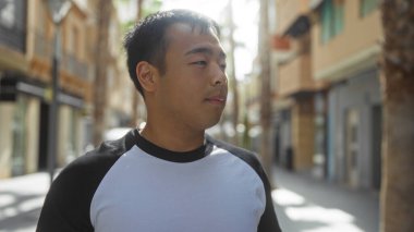 Şehirdeki bir caddede duran yakışıklı genç Çinli bir adam sıradan bir açık hava modası ve şehir hayatının hareketli atmosferini sergiliyor..