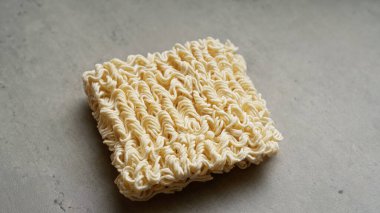 Gri arkaplanda kare hazır erişte bloğunun yakın çekimi.