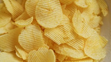 Close-up of crispy potato chips displaying their golden color and wavy texture, perfect for snack promotions or food packaging designs. clipart