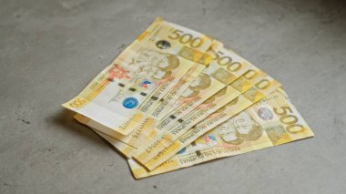 Beton bir yüzey üzerindeki beş yüz Filipinli peso banknotlar Filipinler bağlamında finansal kavramları sembolize eder.