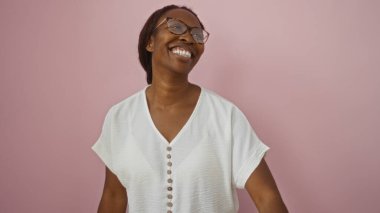 Genç, güzel Afrikalı Amerikalı kadın pembe bir arka planda neşeli bir şekilde gülümsüyor. Işıl ışıl ifadesiyle mutluluğu ve pozitifliği ifade ediyor..