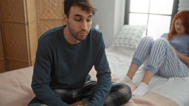 Kadın yatak odasına bakarken pijamalı bir erkek yatakta oturur. İlişkilerinde mesafeli bir ruh hali gösterir. İç mekan sahnesi ve duygusal gerilimi ön plana çıkarır..