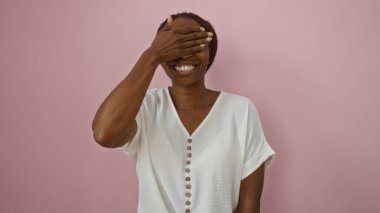 Genç Afrikalı Amerikalı kadın pembe arka planda gülümsüyor.