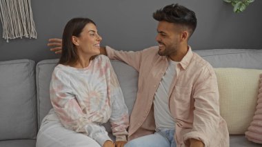 Gülümseyen çift, evlerinde rahat bir oturma odasındaki kanepede oturup eğleniyorlar.