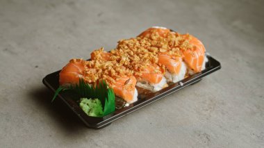 Delicious sushi with salmon topping in black tray on concrete background clipart