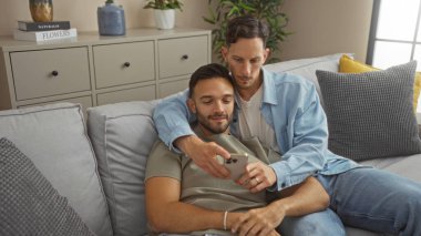 Sevgi dolu bir çift evdeki koltukta oturup cep telefonuna bakar. Modern bir oturma odasında samimi ve samimi bir an yaşarlar.