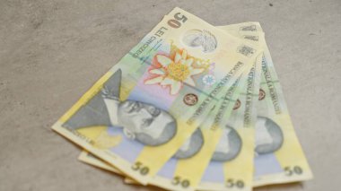 Romen banknotları somut bir yüzeye saçılmış ve Romanya 'dan gelen 50 ley para birimini vurguluyor.