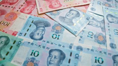 Çin Yuan banknotları dağınık bir şekilde dağılmış, farklı değerler sergiliyor ve canlı renkleri ve Çin 'in para biriminin detaylı tasarımlarını vurguluyor..