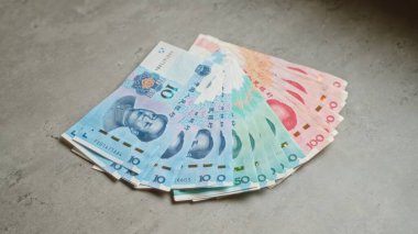 Çin Yuan banknotları beton bir yüzeye yayılmış canlı renkler ve Çin para birimini yansıtan karmaşık tasarımlar sergiliyor..