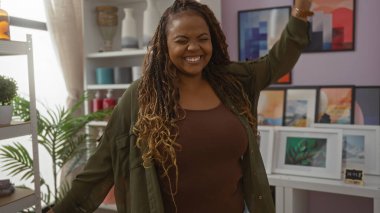 Ayrıca ev dekorasyonu mağazasında gülümseyen Afrikalı Amerikalı kadın. Etrafında çeşitli dekorasyonlar ve ev bitkileri var..