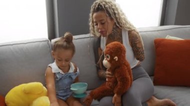 Anne ve kız oturma odasında oyuncak doldurulmuş oyuncaklarla oynuyorlar. Sevgiyi, aile bağlarını ve ev yaşamını gösteriyorlar. Bir kadın ve çocuğunun kapalı mekanda yakın plan fotoğraflarını çekiyorlar.