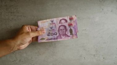 Tayland 'ın parasının dokulu bir yüzeye vurgulandığı somut bir arkaplan üzerine Thai baht para birimi notaları.