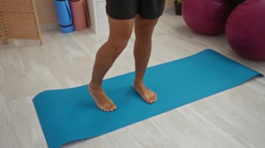 Sağlık merkezinde mavi yoga minderinin üzerinde duran bir adam.