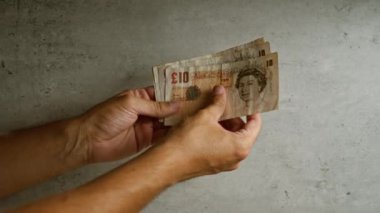 İngiliz sterlinli banknotları tutan adam, İngiltere 'den gelen paraların altını çiziyor..