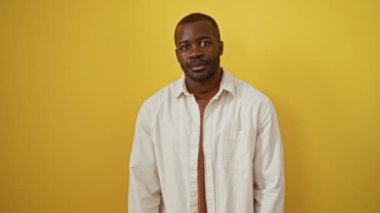 Afro-Amerikan erkeğinin mutlu, başarılı ve izole edilmiş sarı arkaplan üzerinde onaylayıcı duruşu, olumlu ve başarılı titreşimli baş parmak hareketini destekliyor.