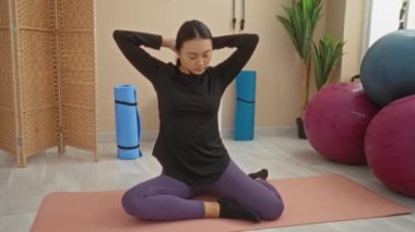 Yoga minderleri ve spor toplarıyla evde yoga yapan bir kadın.