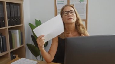 Ofisteki kadın çalışma saatleri boyunca çalışma ortamında odaklanma ve konsantrasyon gösteren kağıtlarla çalışıyor.