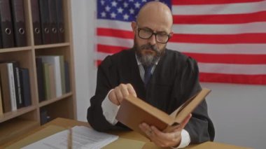 Yargıç cüppeli İspanyol kel adam Amerikan bayrağıyla kitap okuyor.