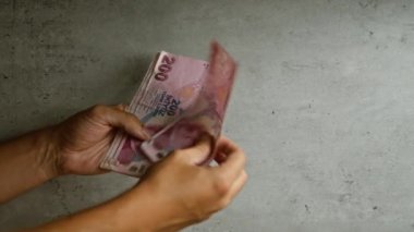 Türk lira banknotlarını sayan bir adam, elinde somut bir geçmişle, Türkiye 'deki mali işlemleri resmediyor.