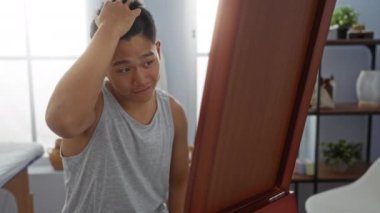 Yansımasına ve saçlarına bakan genç bir adam kaplıca salonundaki minimalist dekoru olan sağlık merkezine bakıyor.