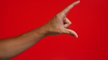 Erkek eli kırmızı arka planda çimdikleme hareketi gösterir, küçük boyutu sembolize eder veya minimum miktarı, küçük veya küçük nesneler kavramını ve hassas ölçümleri ölçer.