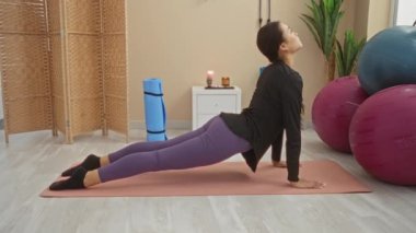 Modern spor salonunda egzersiz minderinde yoga yapan genç bir kadın.