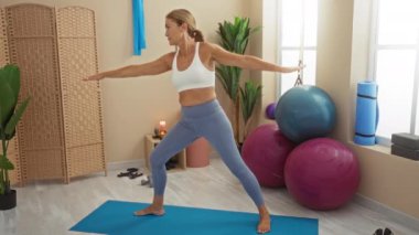 Yoga minderiyle, egzersiz toplarıyla yoga yapan bir kadın. Spor salonu ortamında spor yapmak ve rahatlamak için bitkiler..