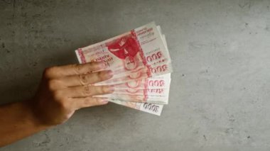 Elle tutulan İzlanda Krona banknotları beton bir arka planda