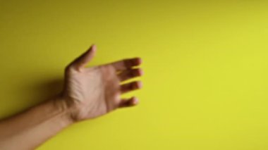 Parmakları açık sarı arka planda ayrıntılı deri dokusunu gösteren bir el..