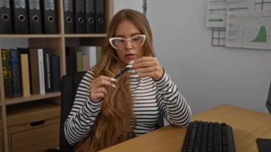 Ofisteki kadın, kitaplarla ve ciltlerle çevrili, kapalı çalışma alanlarıyla dolu bir kalemle belgeyi analiz ediyor.