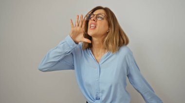 Beyaz arka planda kısık sesle bağıran mavi gömlek, gözlük ve kısa sarı saç giyen bir kadın.