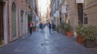 Bulanık insanlar tarihi Roma 'da kaldırım taşı caddesinde yürüyorlar. Parlak gün ışığında dükkanları ve bitkileri var..