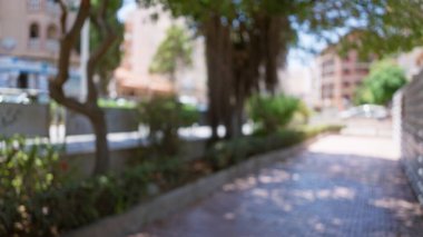 Odaklanmış ağaçlar, kaldırımlar ve yeşil renkli kentsel manzaralı binalar ile bulanık açık hava manzarası.