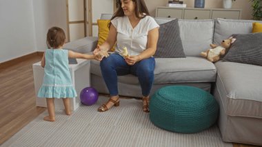 Kanepede oturan bir kadın, küçük bir kızla muz paylaşıyor. Oturma odasının iç tarafında, aile sevgisini ve birlikteliğini gösteriyor..