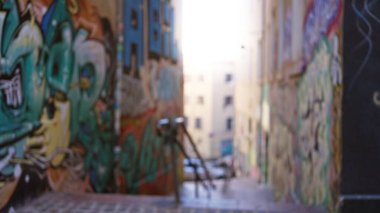 Renkli grafiti ile bulanık şehir sokak sahnesi, gün boyunca cesur bir getto ortamında odaksız sokak ve canlı bokeh arka plan gösterilir.