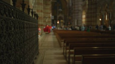 Kilisenin içini ahşap banklar ve arka plandaki insanlarla bulanıklaştırarak, süslü demirciliğe odaklı dinsel bir atmosfer yarattılar..