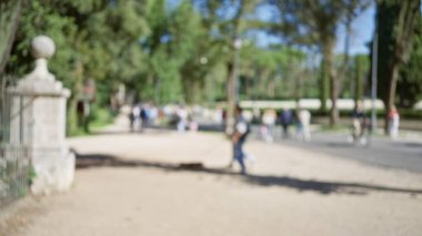 Villa Borghese Bahçeleri 'nde yürüyen ve bisiklete binen insanların bulanık görüntüsü. Arka planda çözünmüş ağaçlar var. Açık havada sakin bir ortam yaratıyor..