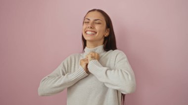 Güzel, esmer, genç, İspanyol bir kadın izole edilmiş pembe arka planda neşeyle gülümsüyor.