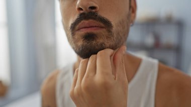 Kapalı kaplıcadaki sakallı genç İspanyol adam nazikçe çenesine dokunuyor.