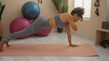 Genç bir kadın büyük egzersiz toplarıyla kapalı spor salonunda yoga egzersizi yapıyor.